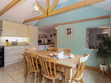 A kitchen with wooden dining table and chairs and cabinets with appliances at Flint Cottage West Caister near Caister-on-Sea