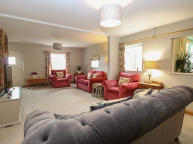 A living room with red armchairs and a grey sofa at Flint Cottage in West Caister near Caister-on-Sea