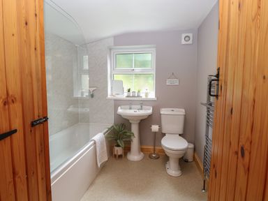 A bathroom with a bathtub toilet and pedestal sink at Flint Cottage in West Caister near Caister-on-Sea