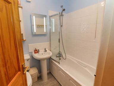 A bathroom with a bathtub shower combination a sink a toilet and a wall mirror at Bluebells in Chapel Stile