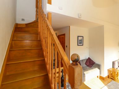 A wooden staircase next to a small gray sofa with cushions in a living area at Bluebells in Chapel Stile