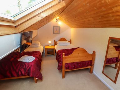 A bedroom with two single beds a bedside table a wall mirror and a skylight at Bluebells in Chapel Stile