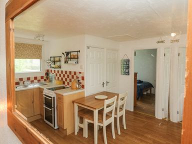 A kitchen with a dining table and chairs next to a stove and sink at Number 24 The Park in Kilkhampton