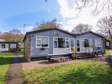 A single-story building with picnic tables outside on a grassy area at Number 24 The Park in Kilkhampton