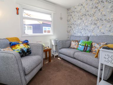 A living room with two gray sofas and a floral wallpaper at Sunny South Shore in Bridlington