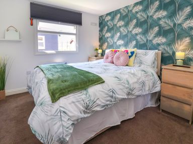 A bedroom with a bed with patterned bedding and pillows bedside tables and lamps at Sunny South Shore in Bridlington