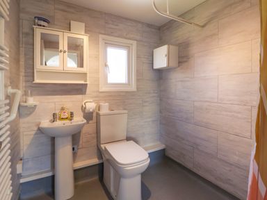 A bathroom with a toilet sink mirror cabinet and window at Sunny South Shore in Bridlington