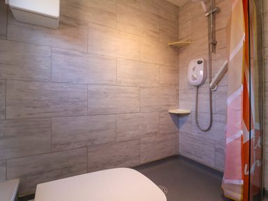 A bathroom with a shower, a shower curtain, and a toilet at Sunny South Shore in Bridlington