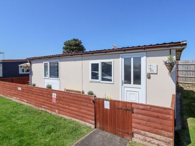 A small house with a white door and windows surrounded by a red wooden fence at Sunny South Shore in Bridlington