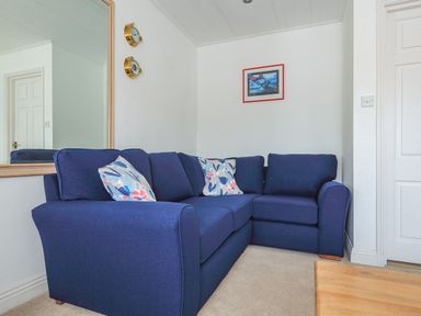 A corner sofa with patterned cushions in a room with a large mirror and framed picture on the wall at 7 Island Quay in Salcombe