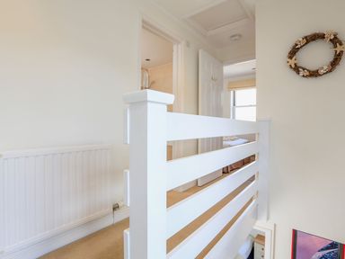 A landing with white railing a radiator and doors leading to a bathroom and a bedroom at 7 Island Quay in Salcombe