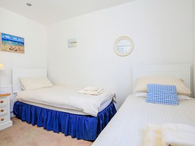 A bedroom with two single beds blue bed skirts and a nightstand with a lamp at 7 Island Quay in Salcombe
