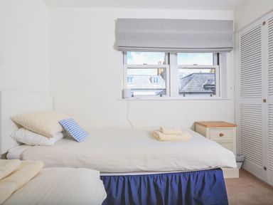 A bedroom with two single beds a window and a bedside table at 7 Island Quay in Salcombe