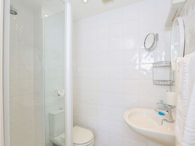 A bathroom with a shower enclosure toilet sink towel and mirror at 7 Island Quay in Salcombe