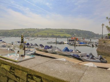 A harbor with several boats docked and a bottle with glasses on a stone wall at 7 Island Quay in Salcombe