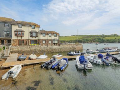 A marina with boats docked by wooden piers and a building with bay windows at 7 Island Quay in Salcombe