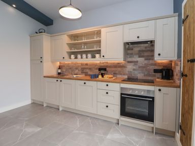 A kitchen with cabinets a sink an oven and countertop appliances at Elliw in Bontuchel near Ruthin