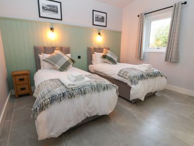 A bedroom with two single beds with pillows and folded towels a nightstand and a window at Elliw in Bontuchel near Ruthin