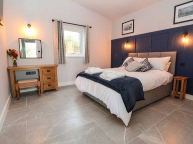 A bedroom with a double bed a wooden desk and stool and a window at Elliw in Bontuchel near Ruthin