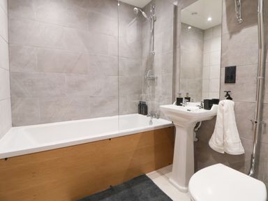 A bathroom with a bathtub shower combination a pedestal sink and a toilet at Elliw in Bontuchel near Ruthin