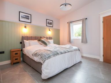 A bedroom with a bed nightstand window and door at Elliw in Bontuchel near Ruthin