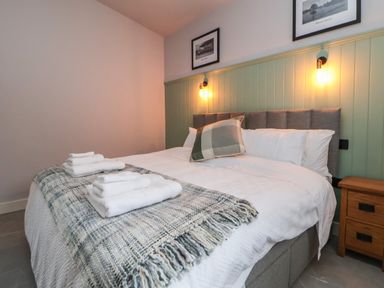 A bedroom with a bed with white bedding and folded towels on a blanket at Elliw in Bontuchel near Ruthin