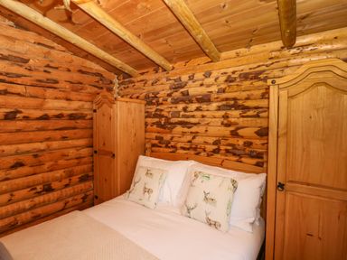 A bedroom with a double bed flanked by two wooden wardrobes in a log cabin at Stag Lodge Holiday Retreat Whitby