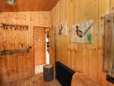 A wooden room with animal paintings on the walls a black radiator and a tree stump stool at Stag Lodge Holiday Retreat Whitby