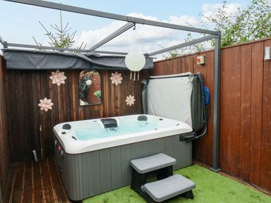 An outdoor hot tub with steps and a wooden fence with decorations at Stag Lodge Holiday Retreat in Whitby