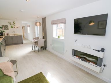 A kitchen and dining area with a mounted television and electric fireplace at The Croft in Shipston-On-Stour
