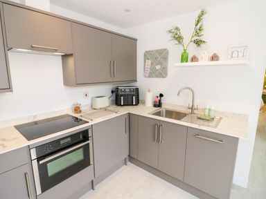 A kitchen with grey cabinets a stove oven sink and countertop appliances at The Croft in Shipston-On-Stour