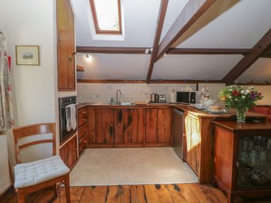 A kitchen with wooden cabinets a skylight and a chair at Beckaford Cottage in Bovey Tracey