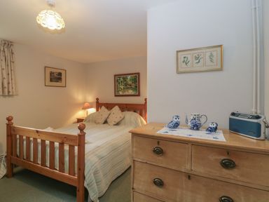 A bedroom with a wooden bed and dresser with blue ceramic owls at Beckaford Cottage in Bovey Tracey