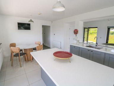 A kitchen with a dining table and chairs a sink and a countertop with a red tray on it at Cushranny Mulranny County Mayo