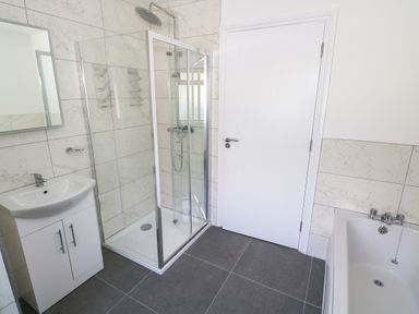 A bathroom with a sink cabinet mirror glass shower enclosure bathtub and a white door at Cushranny Mulranny County Mayo