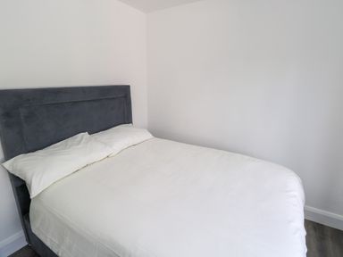 A bedroom with a bed with white bedding and pillows and a dark upholstered headboard at Cushranny in Mulranny County Mayo