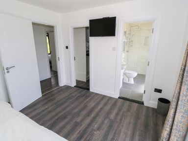 A room with dark wood flooring a wall mounted television and doorways to a bathroom and closet at Cushranny Mulranny County Mayo