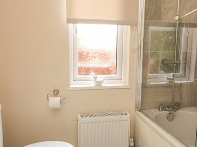 A bathroom with a toilet paper holder radiator window and bathtub with shower at Deer Park 9 - Copse Corner Finlakes Holiday Park near Chudleigh