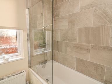 A bathroom with a bathtub shower combination with glass screen and tiled walls at Deer Park 9 - Copse Corner Finlakes Holiday Park near Chudleigh