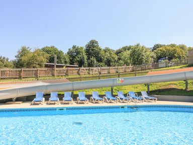 An outdoor swimming pool with blue lounge chairs and a water slide at Deer Park 9 - Copse Corner Finlakes Holiday Park near Chudleigh