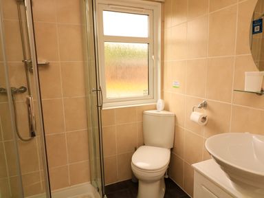 A bathroom with a corner shower enclosure a toilet a window a wall-mounted toilet paper holder and a sink at The Brambles 17 - Conkers Lodge Finlakes Holiday Park near Chudleigh