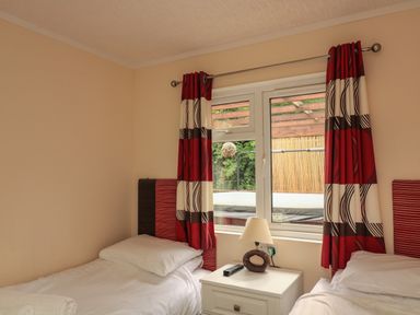 A bedroom with two single beds separated by a nightstand with a lamp and remote at The Brambles 17 - Conkers Lodge in Finlakes Holiday Park near Chudleigh