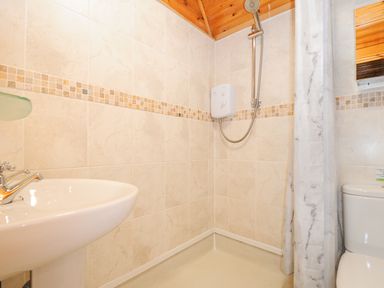 A bathroom with a showerhead sink toilet and shower curtain at Lodge 32 - Cowslip Finlakes Holiday Park near Chudleigh