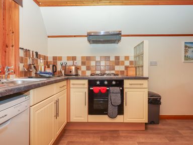 A kitchen with cream cabinets a black oven a gas stove a toaster and a kettle at Lodge 45 - Lazy Bear Finlakes Holiday Park near Chudleigh