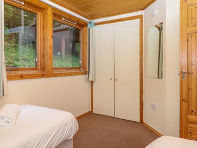 A bedroom with two single beds a window and a white wardrobe at Lodge 45 - Lazy Bear Finlakes Holiday Park near Chudleigh