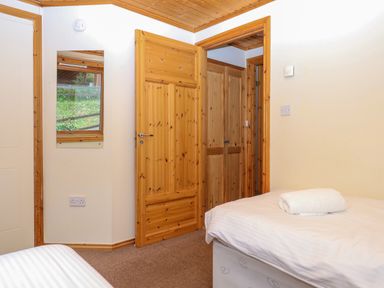 A bedroom with two single beds and a wooden door at Lodge 45 - Lazy Bear Finlakes Holiday Park near Chudleigh