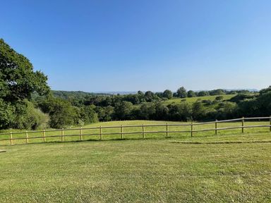 A grassy field with a wooden fence and trees in the distance at Lodge 45 - Lazy Bear at Finlakes Holiday Park near Chudleigh