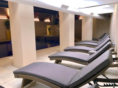 An indoor pool area with cushioned lounge chairs lined up along a tiled floor at Lodge 45 - Lazy Bear Finlakes Holiday Park near Chudleigh