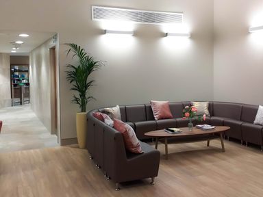 A waiting area with a curved sofa and a wooden coffee table with flowers and magazines at Lodge 45 - Lazy Bear Finlakes Holiday Park near Chudleigh