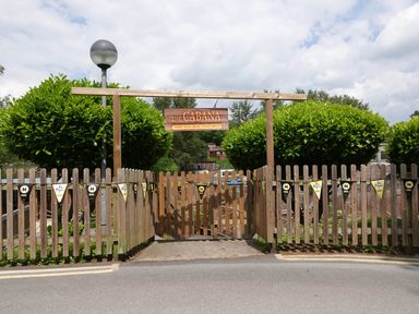 A wooden fence gate with a sign saying The Cabana surrounded by trimmed bushes at Lodge 45 - Lazy Bear Finlakes Holiday Park near Chudleigh